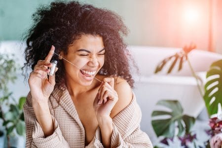 Portrait of happy sensual African american woman dressing bathrobe flossing teeth in bathroom. Plastic less, eco friendly, zero waste concept. Sun glare effect.