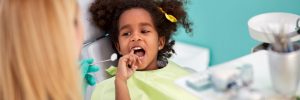 Little child in dental chair show with finger tooth for repairing