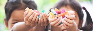 Two asian child girls holding sweet candies in thier hands and share to each other