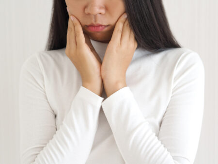 trigeminal neuralgia and temporomandibular joint and muscle disorder in asian woman, She use hand touching her cheek and symptoms fo pain and suffering on isoleted white background.